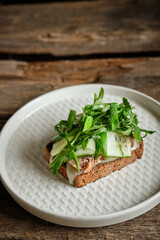 rye toast with cheese, beef, cucumber, arugula, green onions. Top view. Wooden background	