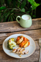 bowl with broccoli, baked potatoes and carrots and fried chicken pieces.