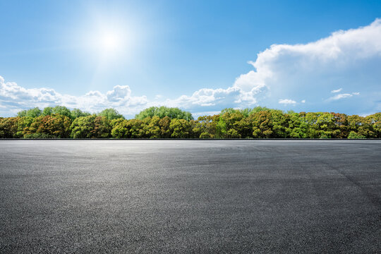 Empty asphalt road with green trees and bright blue sky background - Powered by Adobe