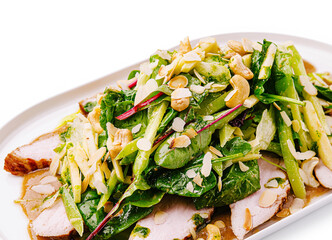 Colorful salad with grilled chicken and almonds served on a platter