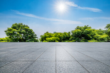 Empty square floor and green trees under blue sky