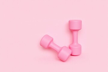 Two pink dumbbells light pink background