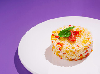 Colorful rice dish garnished with fresh herbs on a white plate
