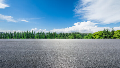 Empty asphalt road with green trees and blue sky on a sunny day