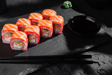 Fresh sushi rolls served on a dark slate plate with dipping sauce