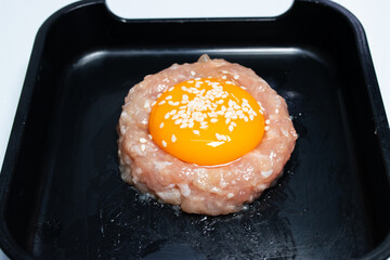 Raw minced pork topped with egg yolk in black tray for serving as shabu.
