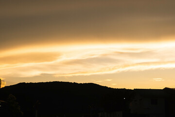 Golden moody clouds by the rays of the dawn sun after sun has just set behind.
