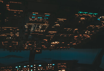 Cockpit view of an airplane during a night-time flight with illuminated instrument panels