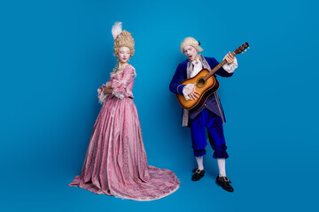 Elegantly dressed couple in vintage costume against blue background symbolizes romantic connection.