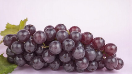 Fototapeta premium A bunch of grapes lies on a light purple background.
