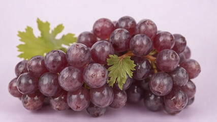 Fototapeta premium A bunch of grapes lies on a light purple background.