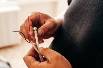 Hands connect colored wires. Electrical work, technical style, light background, details.