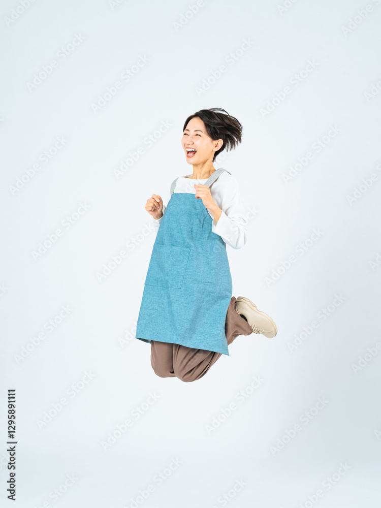 Fototapete ジャンプ、女性、主婦、全身、エプロン、ママ、お母さん、元気、笑顔、ハッピー、喜ぶ、嬉しい、ポジティブ、保育士、介護士、ハウスキーパー、家事代行、ハウスキーピング、ウキウキ、ワクワク、飛躍、アクティブ、飛ぶ、躍動感、アクション、レベルアップ、ステップアップ、挑戦、チャレンジ、成長、料理、キッチン、やる気、楽しい、ラッキー、チャンス、キャンペーン、日本人、ミドルエイジ、中年、30代、40代、写真、広告