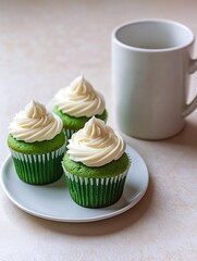 Two green frosting cupcakes on a plate, ready for a sweet treat. Cupcakes in white mug and creamy white frosting on top.