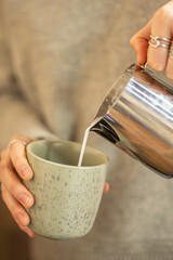 Barista pouring milk for latte art. Barista's hands preparing coffee close-up.