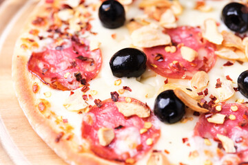 Pizza with salami and mozzarella cheese. Wooden background. Soft focus. Close up.	