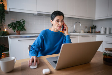 Confident businesswoman multitasks remotely, working on laptop and smartphone. Home office,...