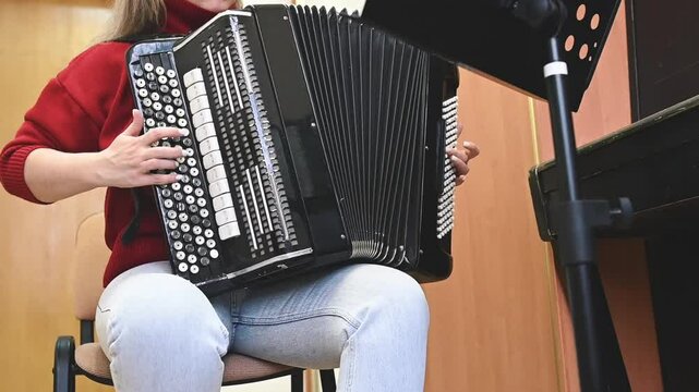 Close-up of bayan buttons as a musician in a red sweater plays with precision. The detailed surface and rhythmic motion highlight the complexity of the instrument and its rich musical tradition