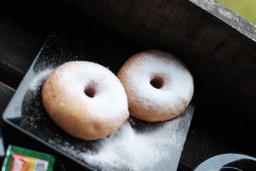 Fresh donuts sprinkled with powdered sugar, perfect for breakfast or a sweet snack.