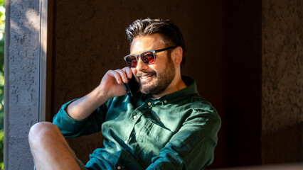 Obraz premium An attractive, slightly overweight middle-aged businessman is having a pleasant phone conversation in a cafe outside his office