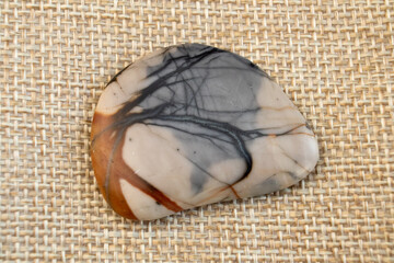 one small natural jasper picasso stone, brown and grey on craft paper background