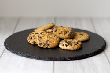 Freshly Baked Chocolate Chip Cookie on black plate and light Background