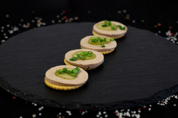 canapes with pate and greens on black plate