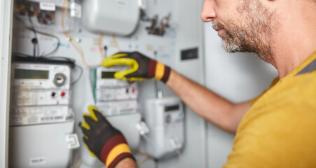 Technician working on a electricity power meter station in a building.