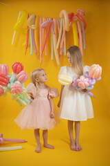 Two little girls with balloons and tulips on a yellow background.