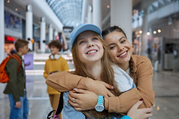 Portrait of teenage girls friends hugging while posing over shopping center