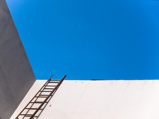 A wall, ladder and blue sky.