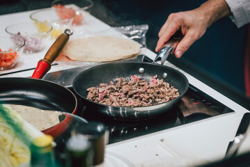 Koch brät Fleisch in der Pfanne