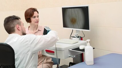 Male doctor examines neoplasms or moles on the woman patient's skin - using special apparatus for dermatoscopy digital dermoscope. Prevention of melanoma and skin cancer. World Cancer Day - Powered by Adobe