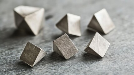 Minimalist Brushed Silver Geometric Shapes Scattered on Dark Concrete Surface