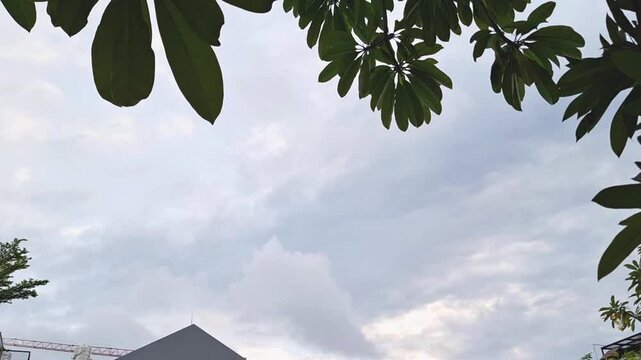 A dynamic hyper-lapse captures the movement of clouds across a cloudy afternoon sky, gracefully passing over a house.
