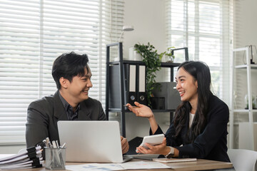 Diverse business partners smiling and discussing financial strategies in a modern office.