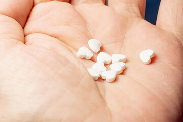 The medical concept of diseases of the human cardiovascular system. Heart-shaped pills on a person's arm. 