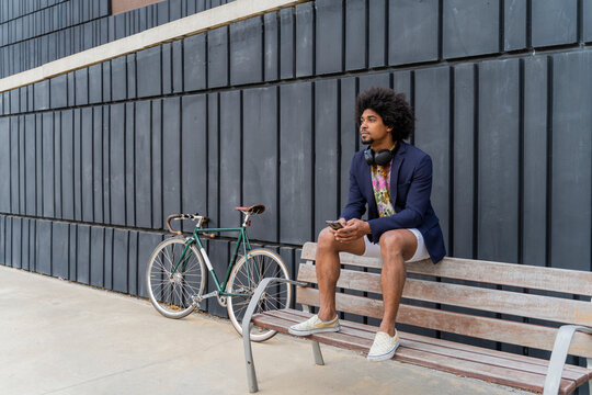 Stylish man with cell phone sitting on a bench