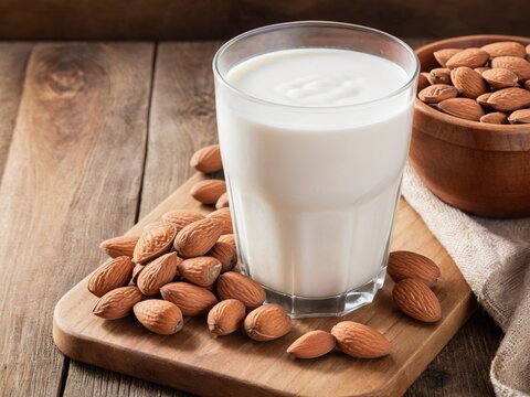 Glass of almond milk and almonds on wooden table