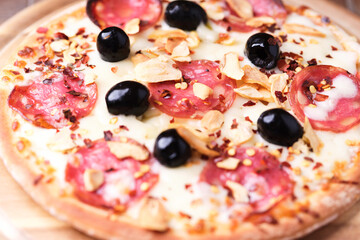 Pizza with salami and mozzarella cheese. Wooden background. Soft focus. Close up.	