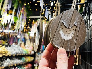 Hanging wooden ornament shaped as egg with chicken design displayed in festive shop