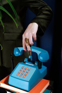 Female hand with ring picking up vintage blue telephone indoors