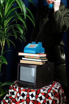 Vintage elegant office studio setup with a blue telephone on stacked books and a television