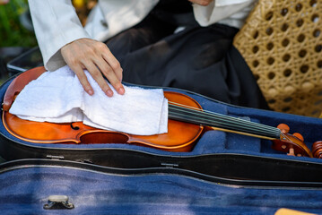 A musician carefully wipes the string of the violin with a soft cloth to clean and maintenance her violin