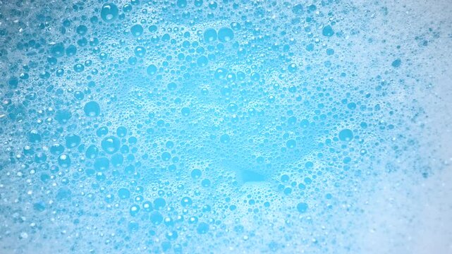 Soap suds in water, bubbles float and burst Abstract white soap foam texture. Concept of cleaning and washing.