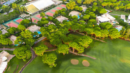Aerial view of a luxury resort with golf course, tennis courts, and private villas among lush greenery
