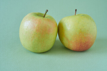 Two ripe orchard apples on a green background.