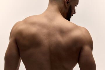 Cropped image of fit man upper back muscles posing shirtless confidently highlighting smooth skin texture and toned muscular physique against white studio background. Male body care and beauty.