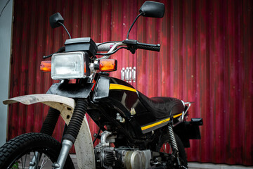 A close-up shot of a motorcycle, showcasing its classic design details against a rustic red door.