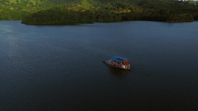 Orbit shot of Ferry tour on Hatillo dam, Cotui, Sanchez Ramirez Province, Dominican Republic. Tourists on the water reserve at sunset. Wide shot.